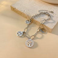 Bracelet en acier inoxydable argenté avec maillons épais et pendentifs arbre de vie circulaires.
