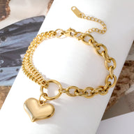 Bracelet en maille gourmette doré 18 carats avec pendentif cœur lisse et fermoir rond ajustable.