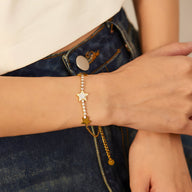 Bracelet fin en maille or avec étoiles brillantes en acier inoxydable porté au poignet féminin.