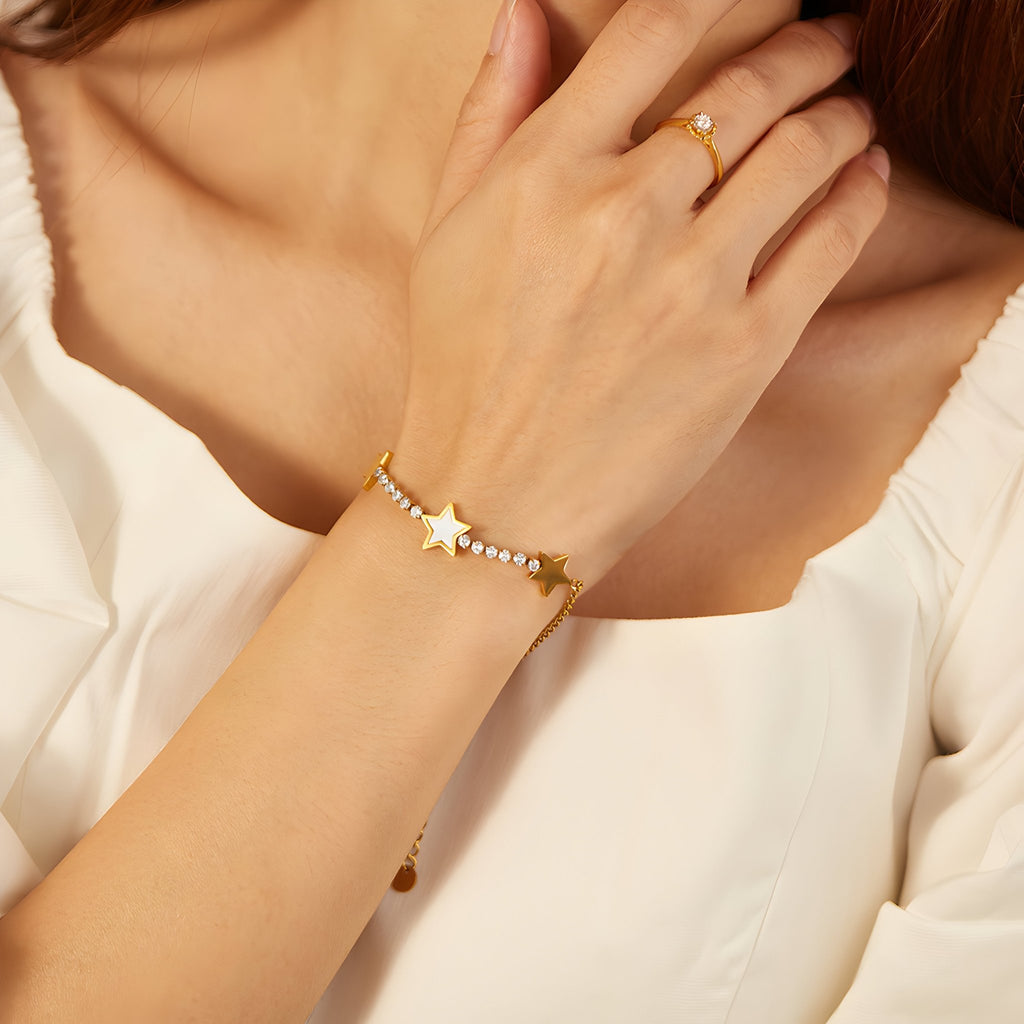 Bracelet en maille dorée avec étoiles scintillantes en acier inoxydable porté au poignet féminin.