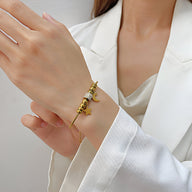 Bracelet serpent doré en acier inoxydable avec pendentif lune et étoiles sur poignet féminin.