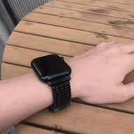 Bracelet en maille V noire épaisse et ajustable pour Apple Watch portée au poignet.