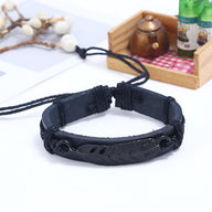 Bracelet noir en microfibre avec grande plume gravée et cordon ajustable.