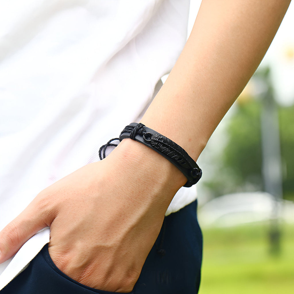 Bracelet noir en microfibre avec grande plume texturée, style mixte, porté au poignet.