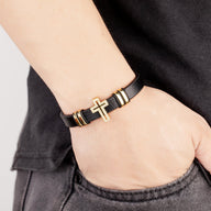 Bracelet en microfibre noir pour homme avec croix chrétienne dorée scintillante et détails métalliques assortis.