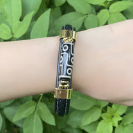 Bracelet homme microfibre noir avec motif tibétain blanc, fermoirs dorés élégants.