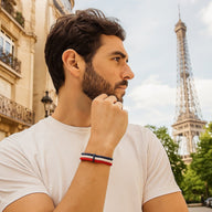 Bracelet en nylon tricolore rouge, blanc et bleu, style tressé, porté au poignet homme.