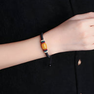 Bracelet noir en nylon avec pierre d'ambre carrée et détails tissés multicolores, modèle mixte.