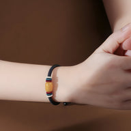 Bracelet mixte en nylon noir avec pierre d'ambre cylindrique et détails métalliques sur poignet.