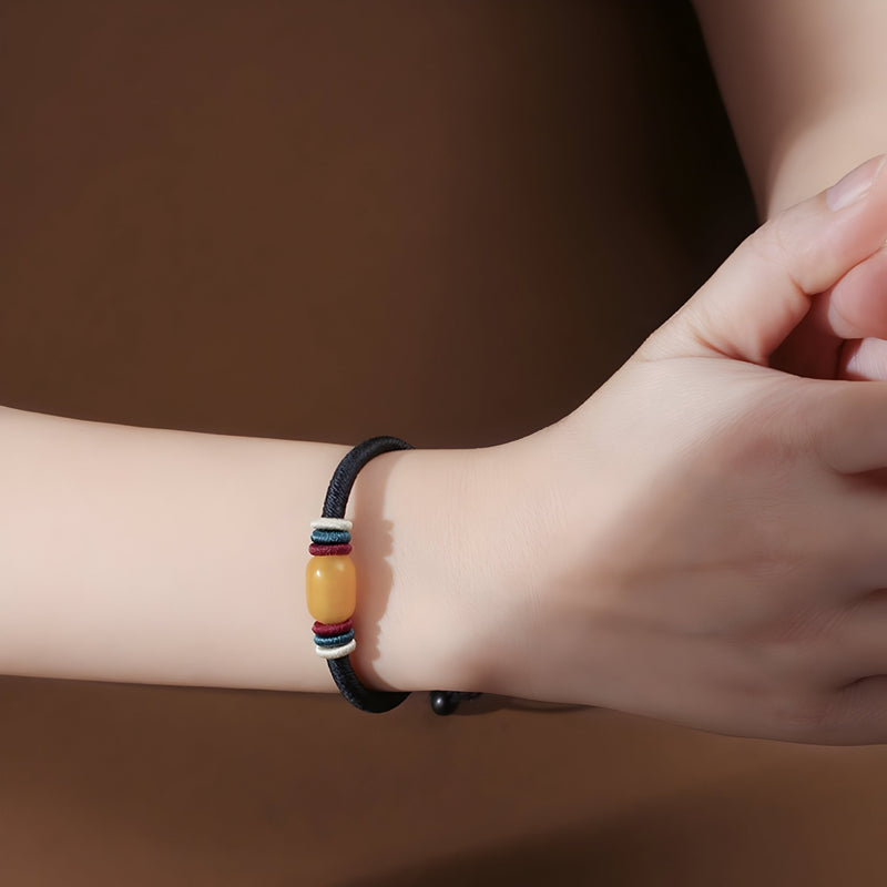 Bracelet mixte en nylon noir avec pierre d'ambre cylindrique et détails métalliques sur poignet.