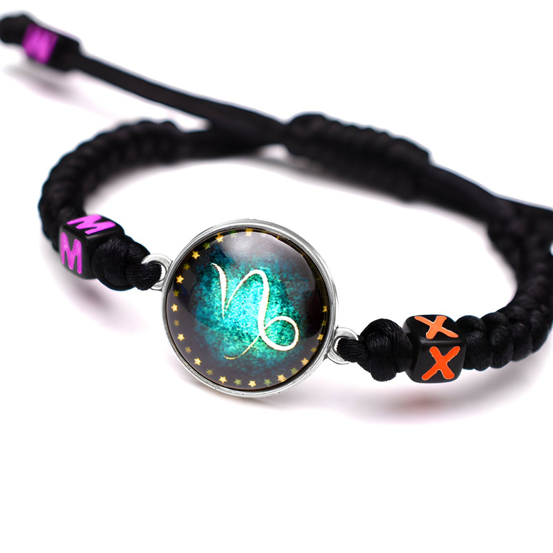 Bracelet en nylon noir tressé avec médaillon signe Capricorne lumineux et perles décoratives roses et noires.