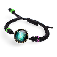 Bracelet en nylon noir tressé avec signe du zodiaque Bélier turquoise sur fond noir scintillant et perles vertes et roses.