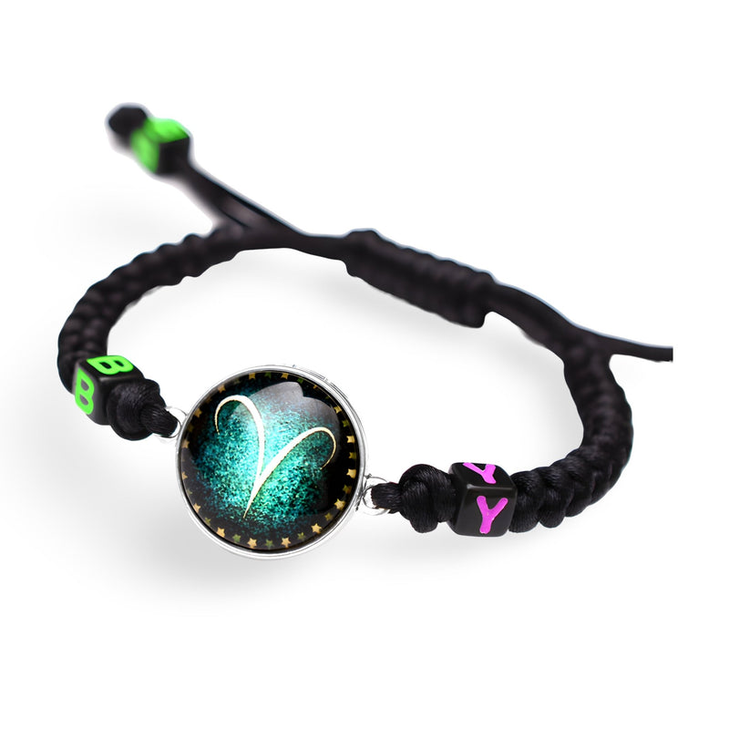 Bracelet en nylon noir tressé avec signe du zodiaque Bélier turquoise sur fond noir scintillant et perles vertes et roses.