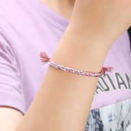 Bracelet en nylon tressé multicolore rose, blanc et bleu avec fines franges aux extrémités.