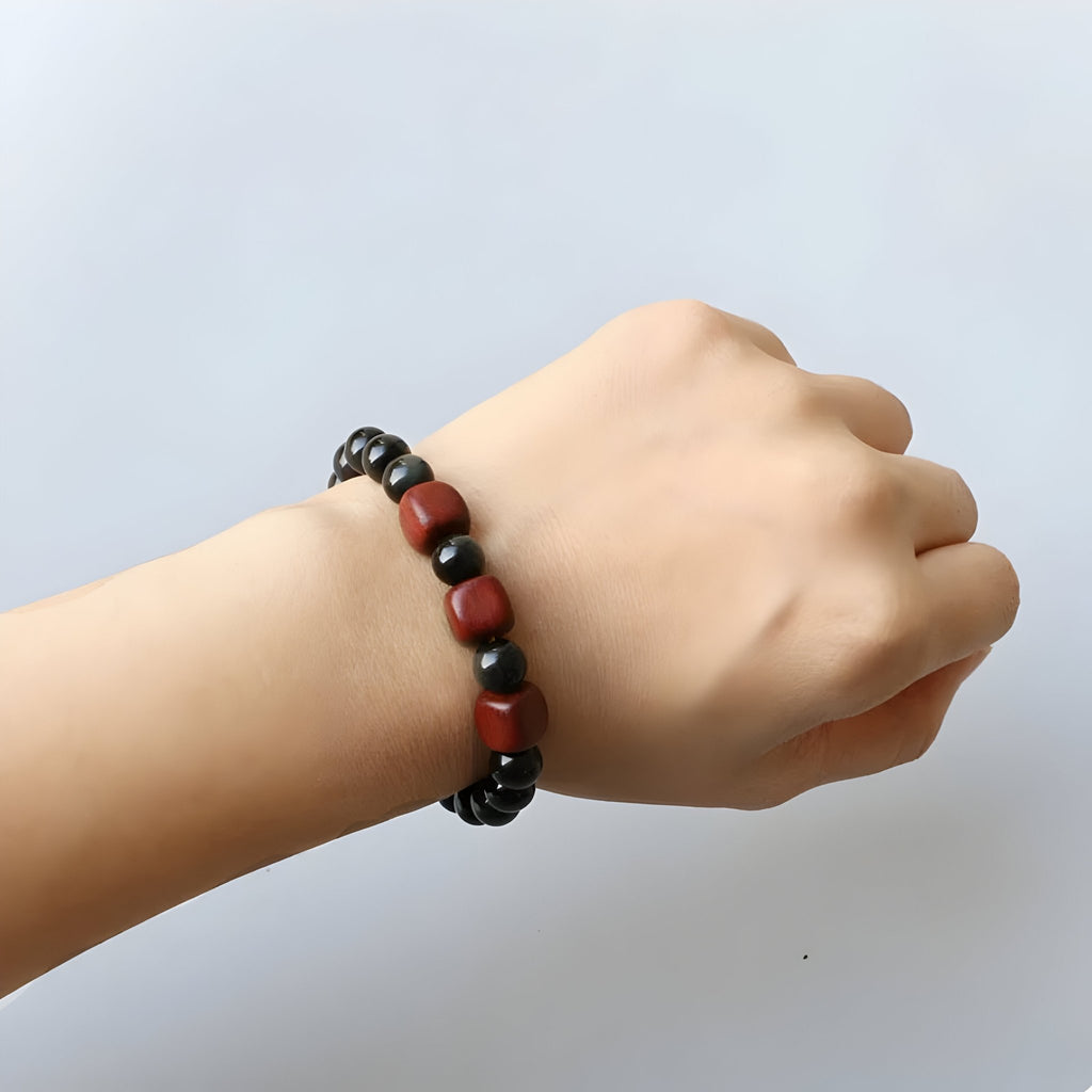 Bracelet mixte en perles d'obsidienne noire et rouges, style délicat, porté au poignet.