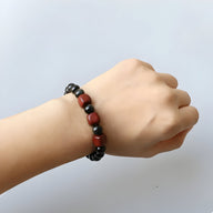 Bracelet mixte en perles d'obsidienne noire et rouges, style délicat, porté au poignet.