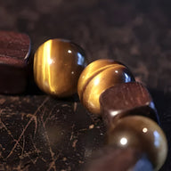 Bracelet mixte en pierres œil de tigre polies et perles en bois d'ébène foncé, finition lisse.