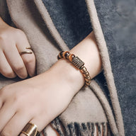 Bracelet femme en œil de tigre et perles de cuivre avec motif central en cuivre détaillé, ton marron chaud.