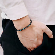 Bracelet fin pour homme en onyx noir et pierres naturelles turquoise porté au poignet.