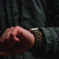 Bracelet en paracorde kaki et noir tressé, ajustable, pour Apple Watch, style robuste et technique.