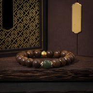 Bracelet femme perles bois marron agrémenté d'une perle verte et d'une perle dorée brillante.