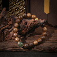 Bracelet femme en perles de bois d'agar marron avec perle de verre verte et détail doré.