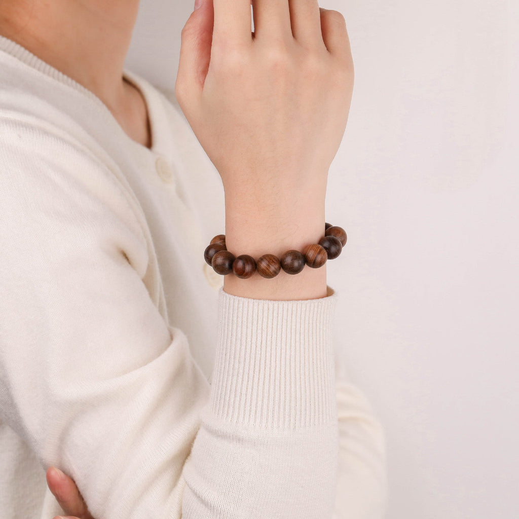 Bracelet en perles rondes en bois de rose marron foncé, porté au poignet, style classique et élégant.