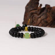 Bracelet femme en perles noires de bois de santal avec perles de verre jaune et verte.