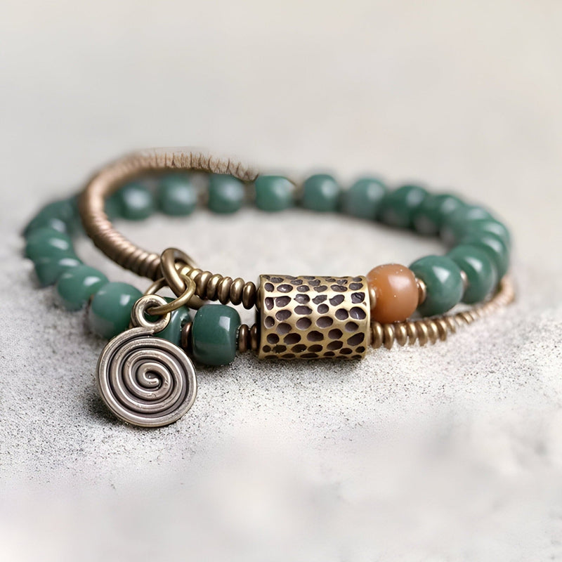 Bracelet femme en perles vertes Bodhi avec breloques cuivre texturé et spirale.