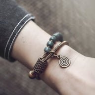 Bracelet femme perles vertes Bodhi et pendentif spirale cuivre sur poignet.