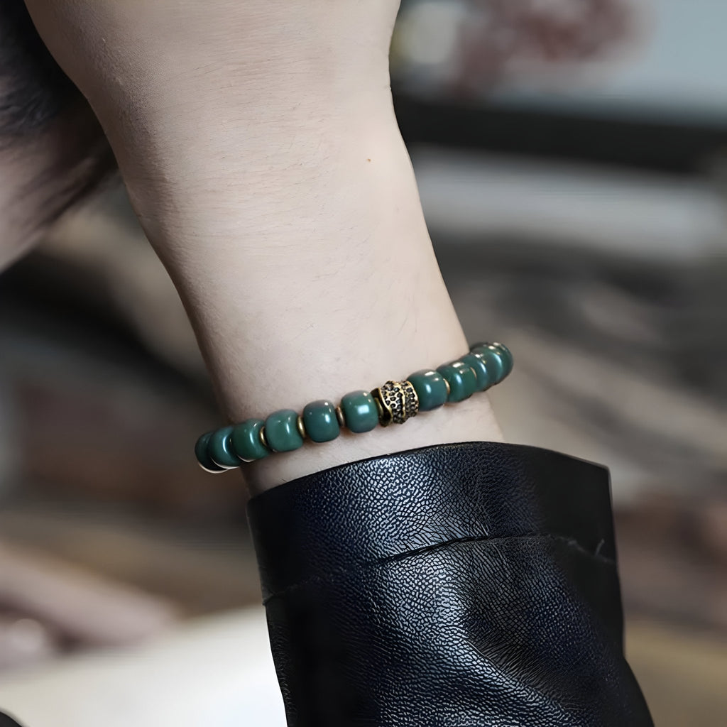 Bracelet mixte en perles vertes de Bodhi avec un détail doré, style Dali, porté au poignet.