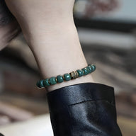 Bracelet mixte en perles vertes de Bodhi avec un détail doré, style Dali, porté au poignet.