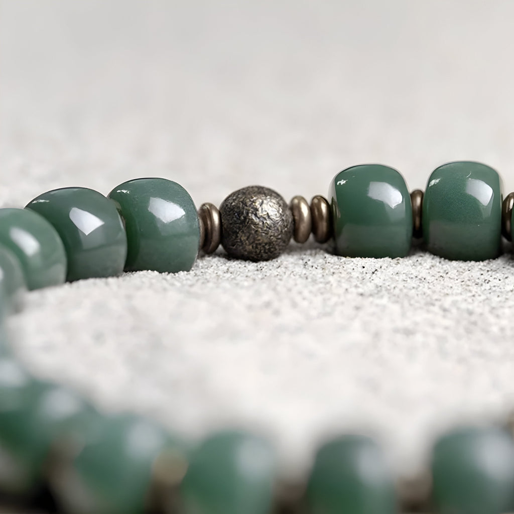 Bracelet mixte perles Bodhi vertes lisses avec perle centrale métallique et petites intercalaires.