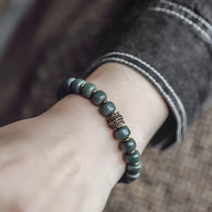 Bracelet mixte en perles de Bodhi vertes mates avec perle centrale décorative en métal vieilli.