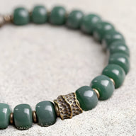 Bracelet mixte en perles de Bodhi vertes avec anneau central texturé en métal doré.