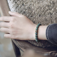Bracelet mixte perles Bodhi vertes avec breloque dorée, porté au poignet, style naturel et zen.