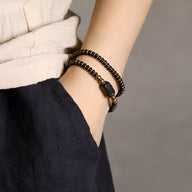 Bracelet double tour en perles de bois d’ébène noir et accents cuivre, style féminin élégant.