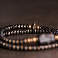 Bracelet double tour en perles de bois d'ébène noir et accents en cuivre, style moderne et élégant.