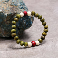 Bracelet mixte en perles de bois vert kaki avec trois perles accent rouge et blanc, style nature.