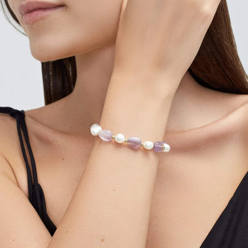 Bracelet ajustable femme perles d'eau douce blanches et mauves élégantes sur cordon fin rose pâle.