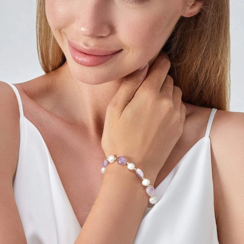Bracelet ajustable en perles d'eau douce blanches et violettes porté au poignet féminin.
