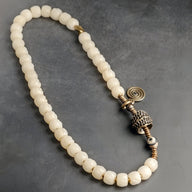 Bracelet femme perles rondes blanches en os de yak avec détails en cuivre spirale et ornements tibétains.