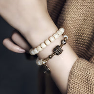 Bracelet femme perles d'os de yak blanches avec breloque cuivre et cordon réglable.