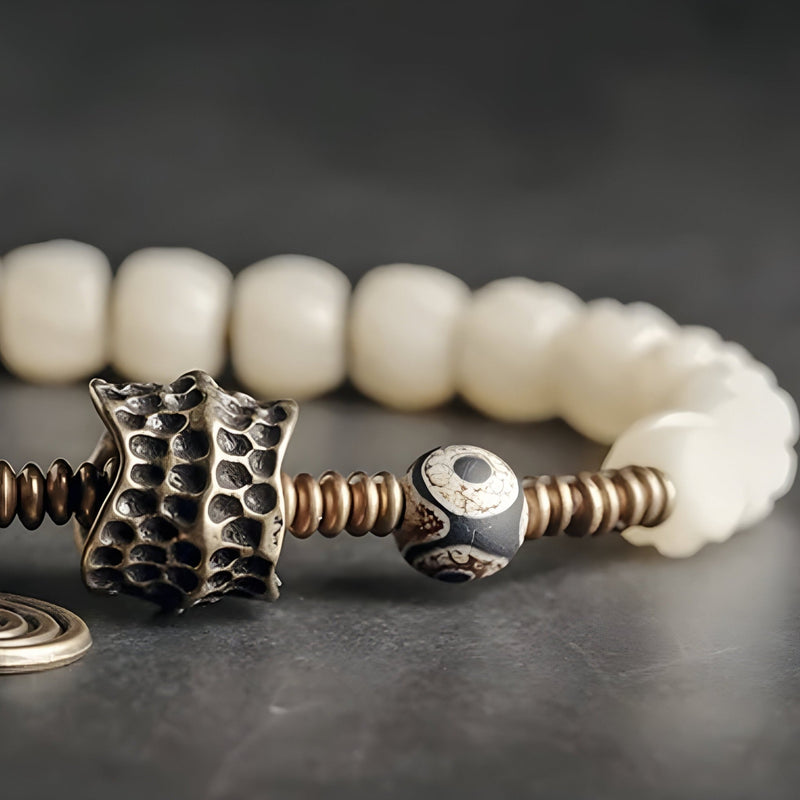 Bracelet femme perles blanches d'os de yak avec pendentif cuivre texturé et perle décorative noire et blanche.