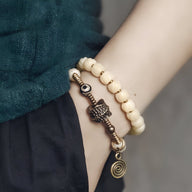 Bracelet femme en perles blanches d'os de yak avec pendentif cuivre et spirale, style tibétain.