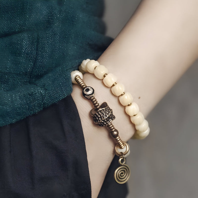 Bracelet femme en perles blanches d'os de yak avec pendentif cuivre et spirale, style tibétain.