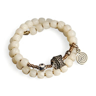 Bracelet double rang en perles blanches d'os de yak avec pendentifs cuivrés spirale et motif central travaillé.