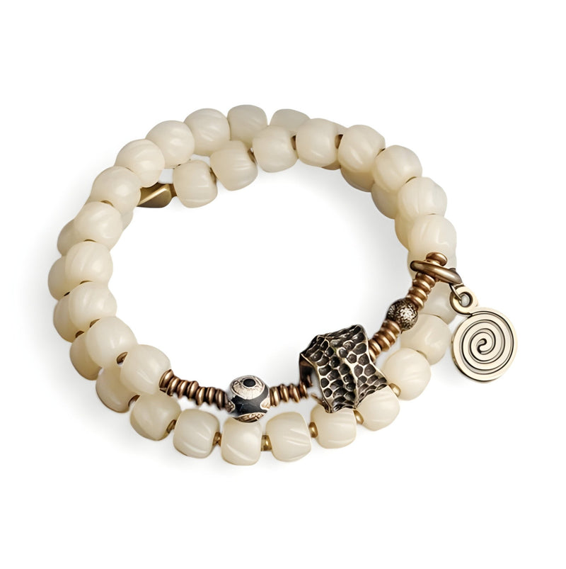 Bracelet double rang en perles blanches d'os de yak avec pendentifs cuivrés spirale et motif central travaillé.