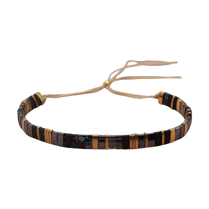 Bracelet ajustable femme en perles japonaises noires et dorées avec lien beige en tissu.