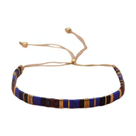 Bracelet ajustable en perles japonaises bleu, marron et doré avec fermeture coulissante en corde beige.